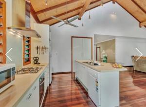 cocina grande con suelo de madera y armarios blancos en Treetops Retreat Cairns, en Cairns
