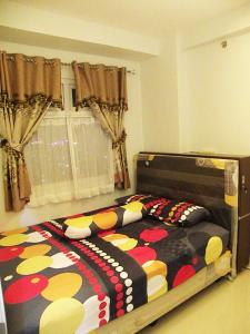 ein Schlafzimmer mit einem Bett mit einer bunten Bettdecke in der Unterkunft Apartment Green Pramuka ~ OCR in Jakarta