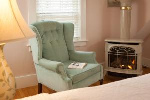a bedroom with a green chair and a fireplace at Sugar Hill Inn in Sugar Hill