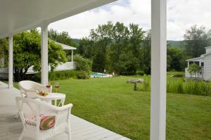 a porch with two chairs and a table with a glass of wine at Sugar Hill Inn in Sugar Hill