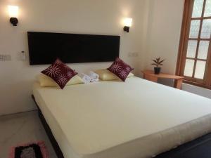 a large white bed with pillows on top of it at Monara Backpacker Inn Unawatuna in Unawatuna