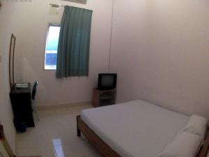 una piccola camera con letto e televisore di Wisma Maharani a Wanci