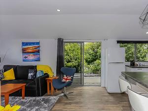 a living room with a black couch and a kitchen at Harbour Heights 2 in Tauranga