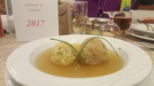 a white plate of food with dumplings on a table at Hotel Grizzly in Folgaria