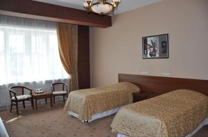 een slaapkamer met 2 bedden, een tafel en een raam bij Meridian in Saransk