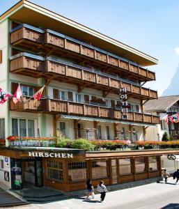 un edificio con gente caminando delante de él en Hotel Hirschen - Grindelwald, en Grindelwald