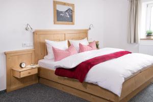 ein Schlafzimmer mit einem großen Bett mit roten und weißen Kissen in der Unterkunft Chalet Hageberg ab Mai freie Fahrt mit Bergbahnen in Bolsterlang
