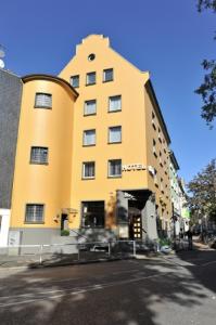 a tall yellow building on the side of a street at Hotel Bergischer Hof in Ratingen +13 photos