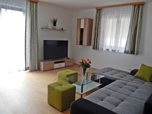a living room with a couch and a tv at Haus Seehof - Ferienhaus in Abersee 