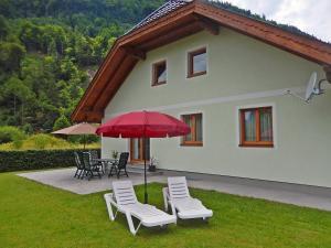 un grupo de sillas y una sombrilla frente a una casa en Haus Seehof - Ferienhaus, en Abersee