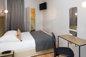 ベルサイユにあるア ロテル デ ロワのベッドとデスクが備わるホテルルームです。