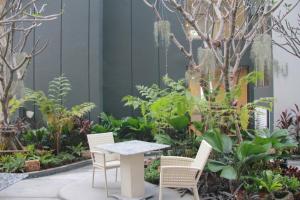 a table and chairs in a garden with plants at Stay with Nimman Chiang Mai in Chiang Mai