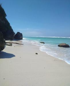 une plage de sable avec des rochers et l'océan dans l'établissement Tanjung Sari Inn, à Nusa Dua