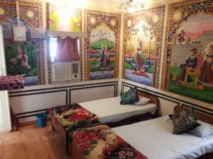 een kamer met 2 bedden en schilderijen aan de muur bij Hotel Shekhawati, A boutique stay in Mandāwa
