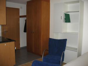 アローザにあるHaus Sunnaplatzの青い椅子とキャビネット付きの客室です。