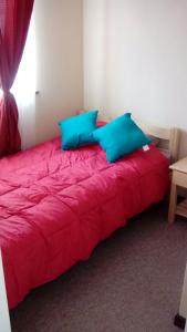 1 cama roja con almohadas azules en una habitación en Casa Veraneo Los Robles Pucon, en Pucón