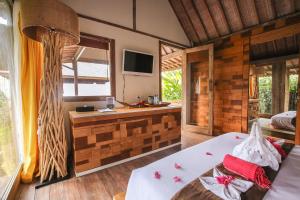 a room with a bed and a television in a room at Camilla Resort in Gili Air