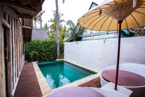 a patio with an umbrella and a swimming pool at Camilla Resort in Gili Islands