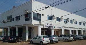 Hotel Palmas Tocantins في بالماس: مبنى أبيض فيه سيارات تقف في موقف للسيارات