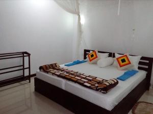 a bedroom with a large bed with colorful pillows at Little Cottage in Ella