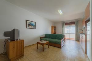 a living room with a green couch and a tv at Apartamentos Paula Bela by Garvetur in Quarteira