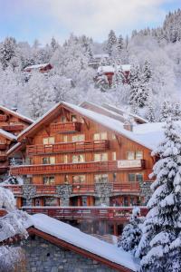 een groot houten gebouw bedekt met sneeuw bij Hotel Le Tremplin in Méribel