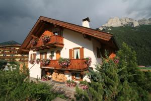 una casa con cajas de flores a un lado. en Appartamenti Majon Ladina en Vigo di Fassa