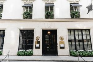 - un bâtiment blanc avec des portes et des fenêtres noires dans l'établissement Le Burgundy Paris, à Paris