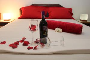 a bottle of wine and a glass and roses on a bed at Apartments Perezaj II in Ulcinj