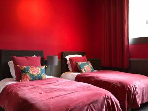 two beds in a room with red walls at Maison d'hôtes Bordeaux Centre Le Patio de l'Intendance in Bordeaux