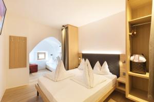 una camera da letto con un letto bianco con cuscini bianchi di Belvenu Boutique Hotel a Glorenza