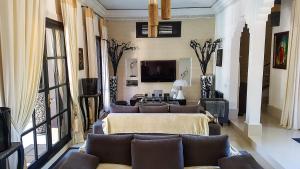 uma sala de estar com sofás e uma televisão e um sofá em Villa Mano em Marraquexe