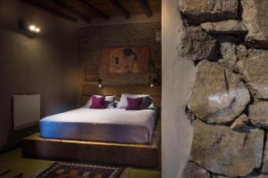 1 dormitorio con 1 cama en una pared de piedra en Puesto Victoria - Adults only en Yacanto