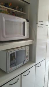 a kitchen with a microwave and a refrigerator at Apartamento Riviera in Bertioga