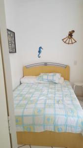 a bed with a blue and white comforter in a room at Apartamento Riviera in Bertioga