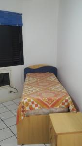 a small bedroom with a bed and a table at Apartamento Riviera in Bertioga