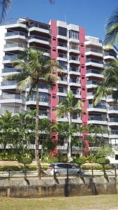 a person carrying a surfboard in front of a large building at Apartamento Riviera in Bertioga