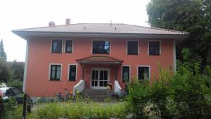 een oranje huis met een veranda en een trap bij Fewo 2 Ferienwohnung Waren Müritz - Haus Buchen am Tiefwarensee - 2 Zi in Waren