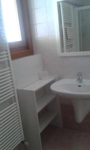 a white bathroom with a sink and a mirror at Casa Adile in Sappada