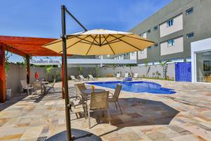 a patio with a table and an umbrella next to a pool at Comfort Mogi Guaçu in Mogi Guaçu
