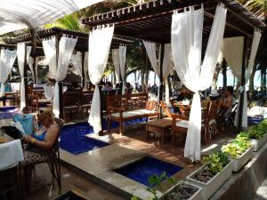 una mujer sentada en un restaurante con sombrillas blancas en Cond. Village Van Cartier, en Fortaleza