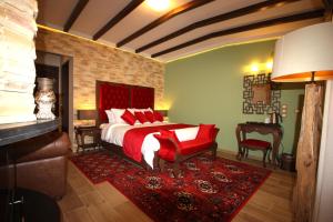 um quarto com uma cama com almofadas vermelhas e uma cadeira vermelha em Archontiko Metsovou Luxury Boutique Hotel em Metsovo