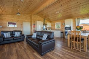 ein Wohnzimmer mit 2 Ledersofas und einer Küche in der Unterkunft The Chalet, Holidays for All in Dunbar