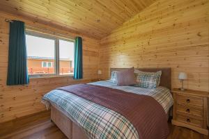 een slaapkamer met een bed in een houten hut bij The Chalet, Holidays for All in Dunbar