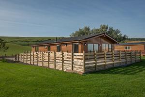 eine Holzhütte mit einem Zaun davor in der Unterkunft The Chalet, Holidays for All in Dunbar