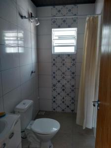 baño con aseo y lavabo y ventana en Recanto Camaleão, en Florianópolis