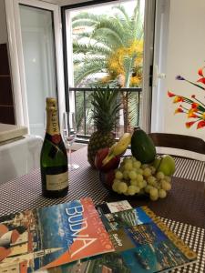 a table with a bottle of wine and a bunch of fruit at Apartment Viva in Budva