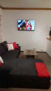 a living room with a couch and a tv on the wall at Penzion Čistá in Černý Dŭl