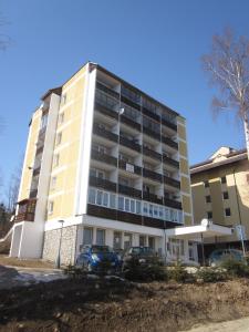 an apartment building with cars parked in front of it at Apartmán Zdravie Horný Smokovec in Vysoke Tatry - Horny Smokovec