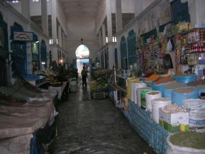 Dar es Salam-Alta في أصيلة: ممر سوق فيه شخص يمشي في محل